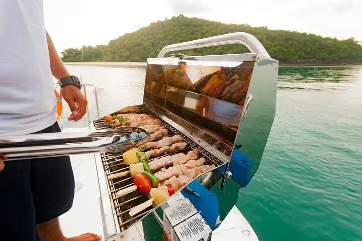 Grilled skewers cooking on a barbecue aboard a boat, part of the Angra and Ilha Grande tour with drinks included.