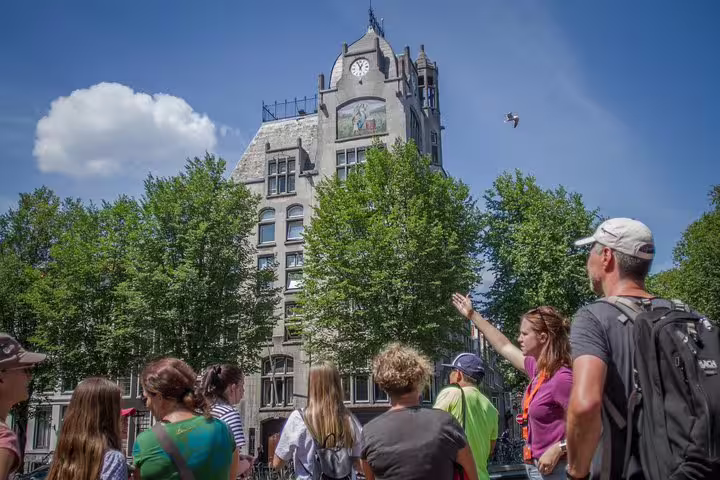 Tour group explores historic buildings in Amsterdam's Jewish Cultural Quarter on the Anne Frank Walking Tour under a clear blue sky.