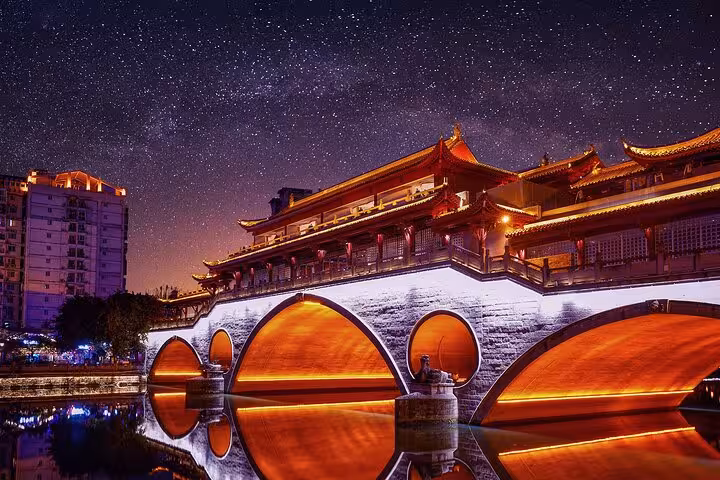 Illuminated Anshun Bridge in Chengdu under a starry night sky, reflecting on the Jin River during a private city tour.