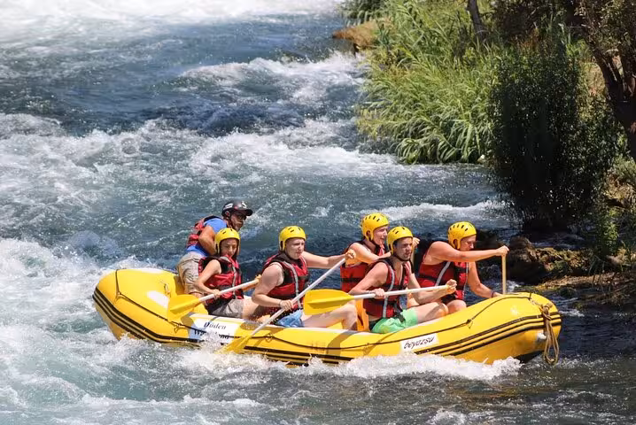 Group rafting in a yellow inflatable boat on Antalya river rapids, guided adventure tour with helmets
