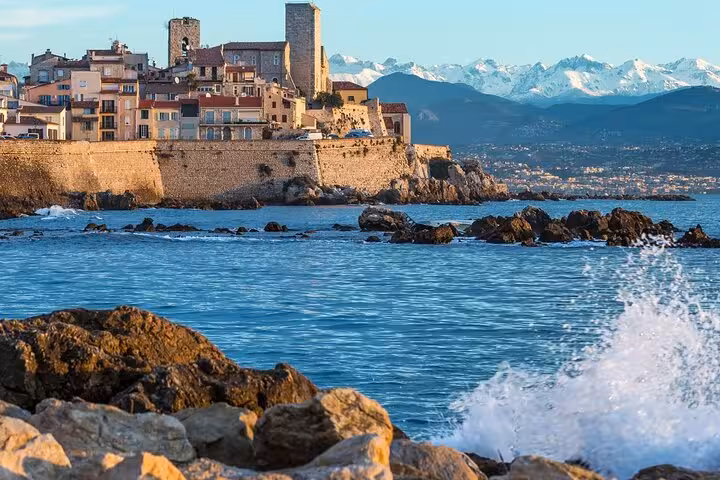 Antibes coastline with historic architecture and snow-capped Alps in the background, ideal for French Riviera tours.