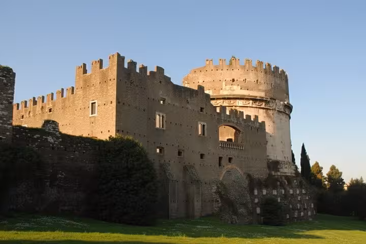Majestic ancient fortress with a cylindrical tower on the Appian Way, bathed in warm sunlight.