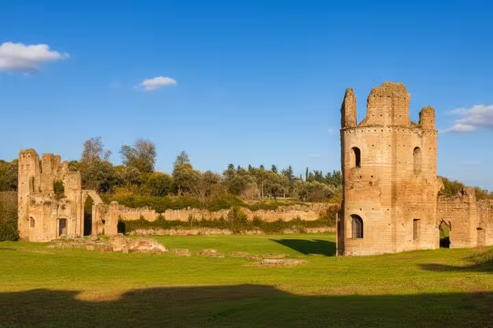 Explore ancient ruins along the scenic Appian Way on a private tour, featuring historic Roman structures and vibrant greenery.