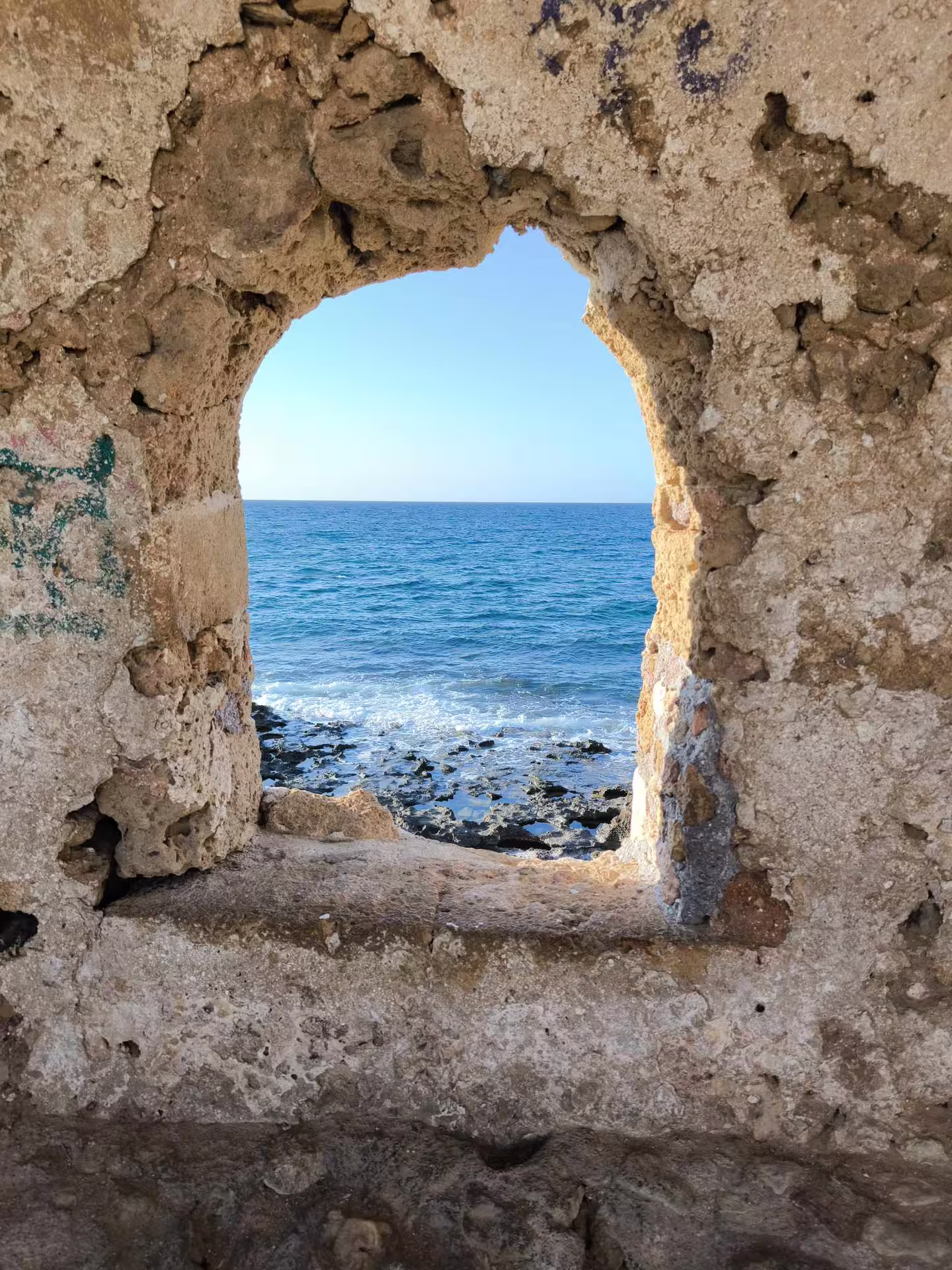 Stunning sea view through a stone archway in Chania, capturing beauty on the Aptera & Chania tour.