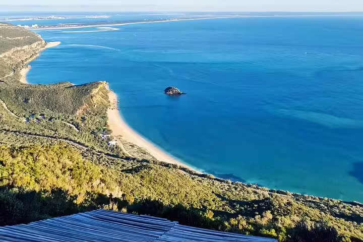 Scenic view of Arrábida coastline with turquoise waters, lush hills, and sandy beaches, ideal for nature and wine tasting tours.