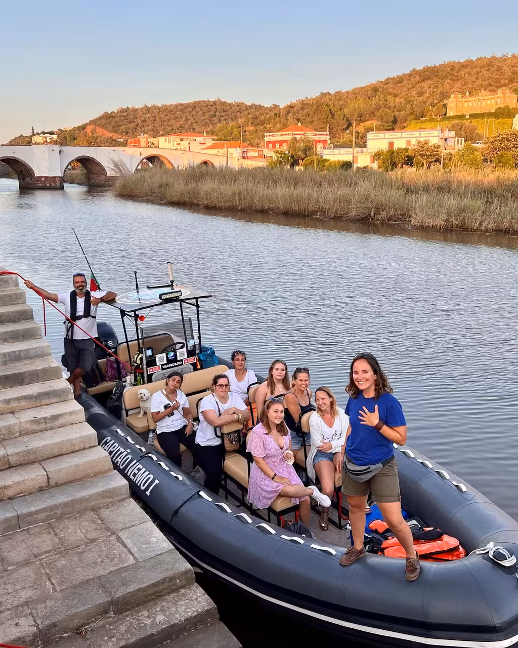Happy group boarding a private Arade River boat tour to historic Silves, passing the old bridge and Algarve riverside scenery