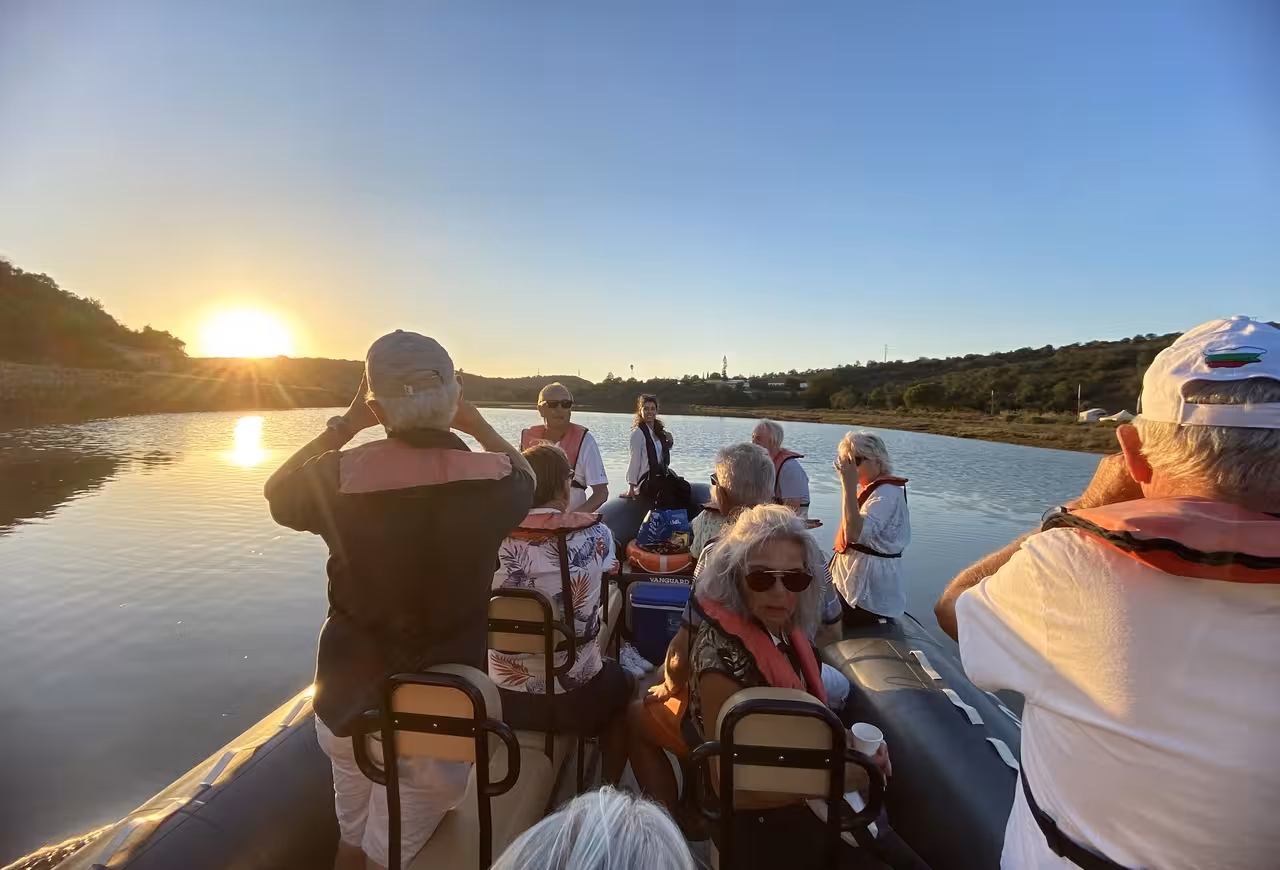 Small group enjoying a private boat tour on the Arade River at golden sunset en route to historic Silves in the Algarve