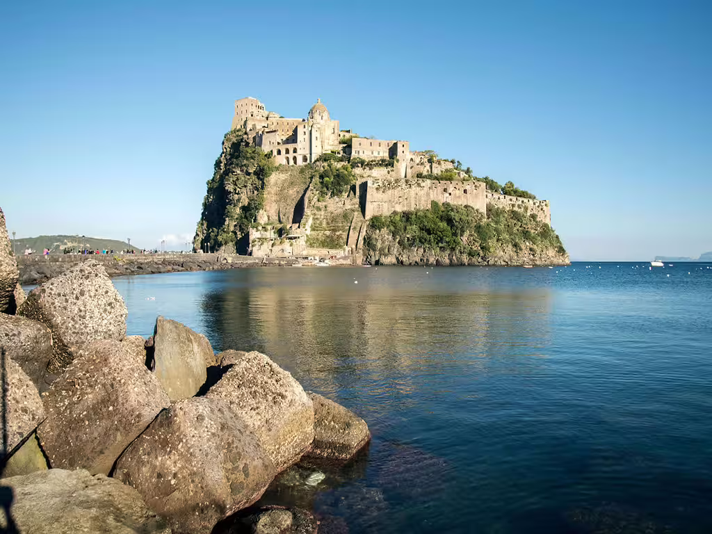 Aragonese Castle on Ischia island rising above the Tyrrhenian Sea, seen from a Naples boat tour with rocky shoreline