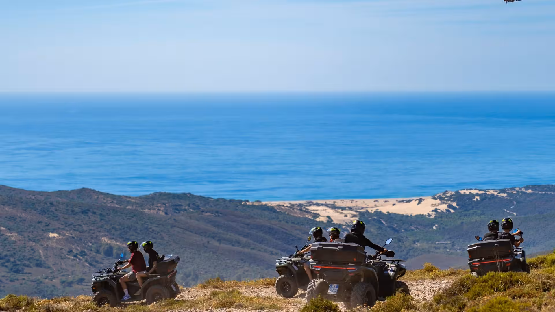 Adventurers on ATVs enjoy breathtaking coastal views of Arbus, riding along scenic trails between dunes and hills.
