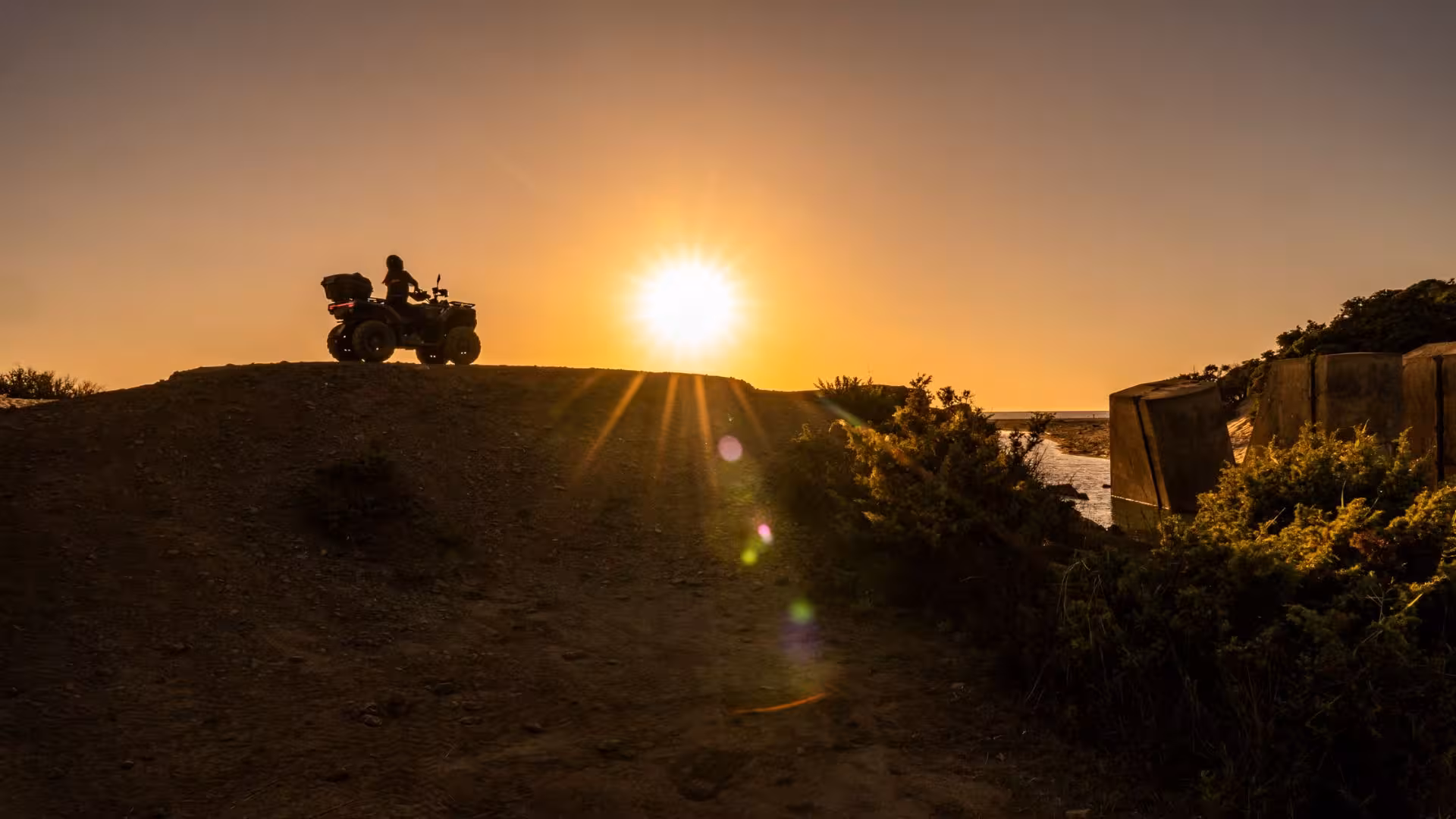 Silhouette of an ATV rider against a vibrant sunset in Costa Verde, highlighting the adventure of the Arbus tour.