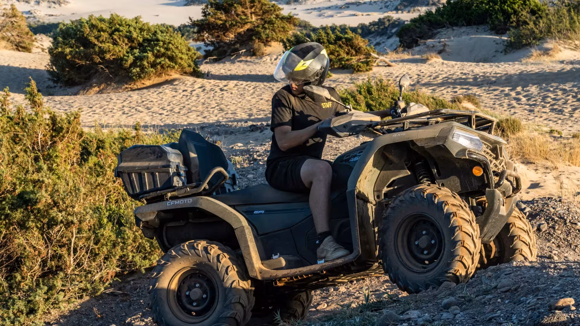 ATV rider navigates sandy dunes surrounded by lush greenery on an Arbus adventure in Costa Verde.