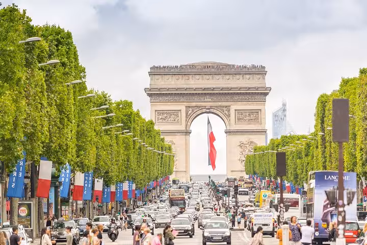 Arc de Triomphe framed by Champs-Élysées trees and traffic, highlight of a private Paris walking tour
