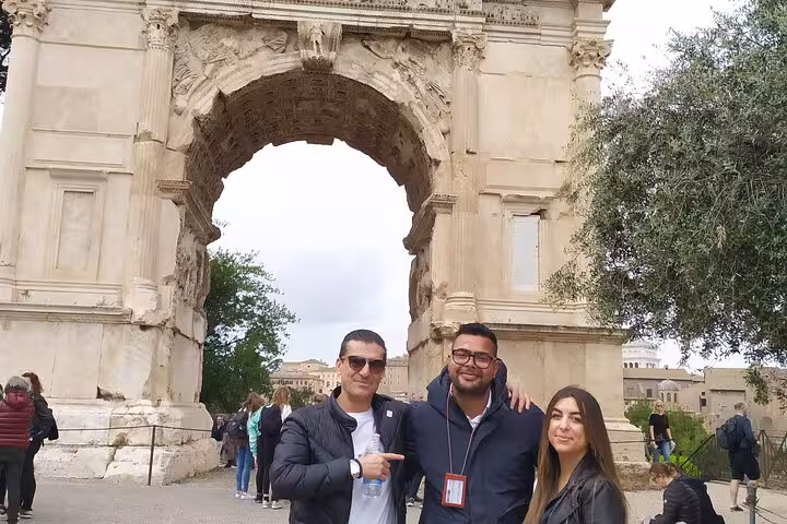 Visitors pose in front of the Arch of Titus during a private tour of Ancient Rome, capturing the essence of Roman history.
