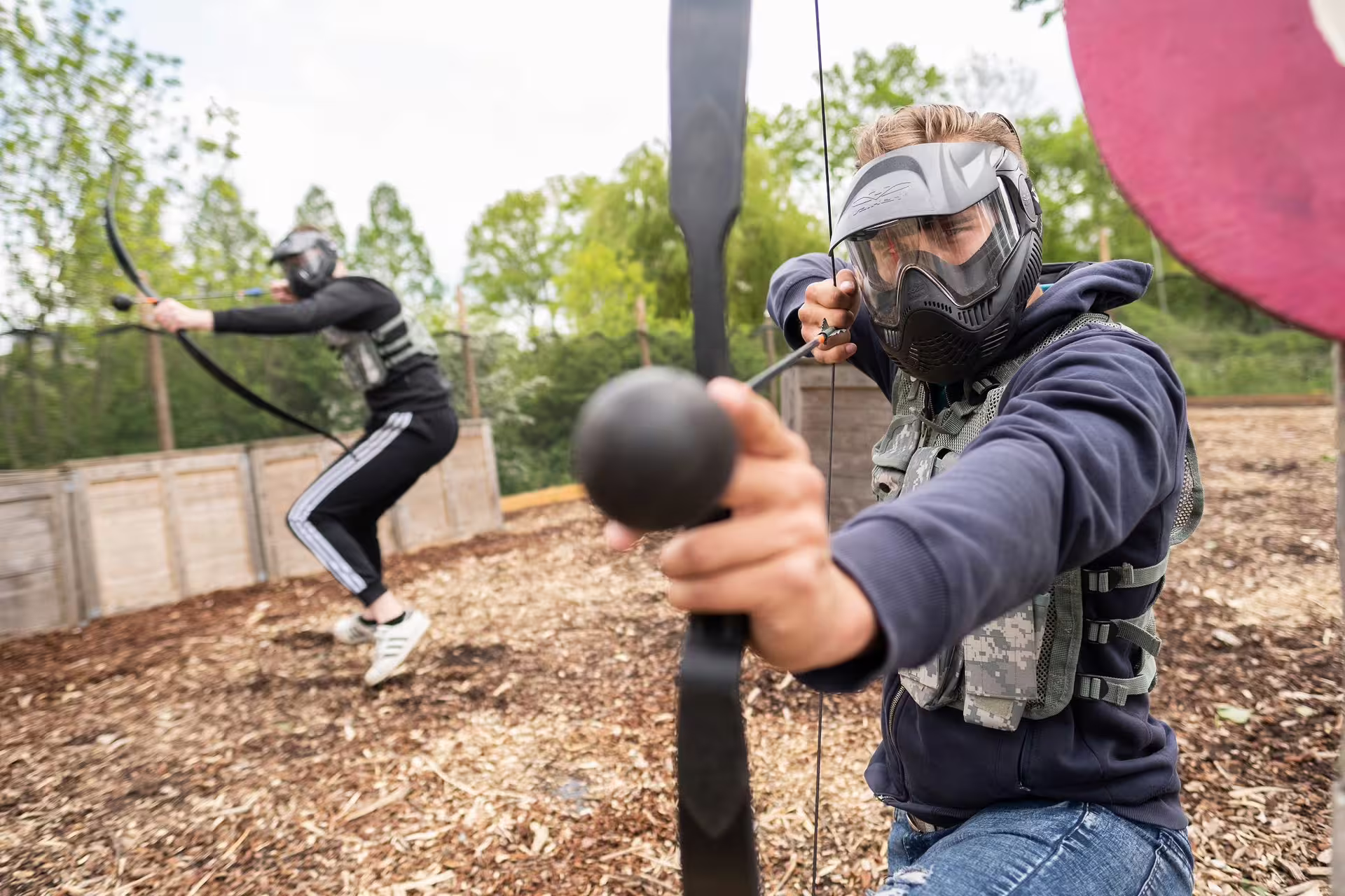 Two players in masks draw bows during Archery Tag in Amsterdam, outdoor group activity with foam arrows