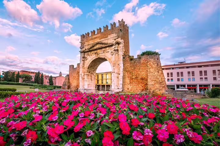 Arco d’Augusto in Rimini with vibrant flowerbeds, featured landmark on a self-guided scavenger hunt highlights tour