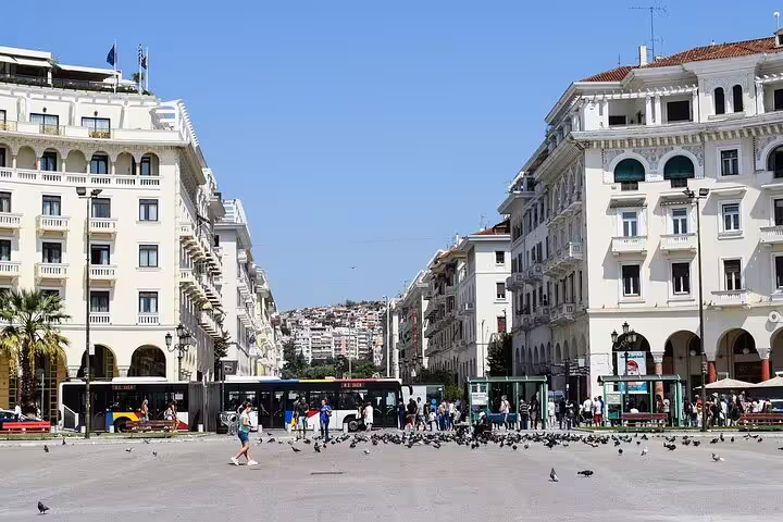 Aristotelous Square in Thessaloniki bustling with people and pigeons, showcasing grand architecture and vibrant city life.