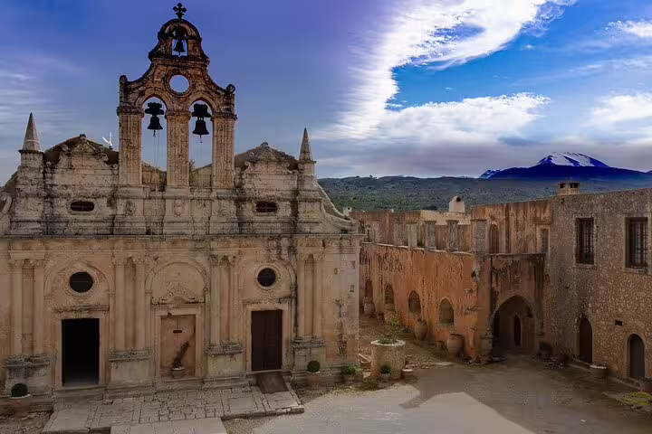 View of Arkadi Monastery's historic facade against a mountainous backdrop in Rethymno, Crete.