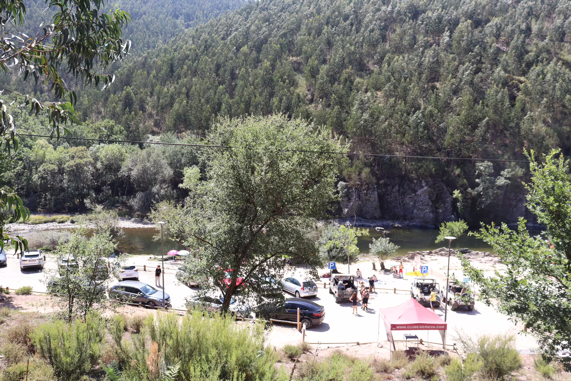 Scenic view of visitors exploring the lush landscape near Arouca 516 Bridge and Paiva Walkways, surrounded by verdant forest.
