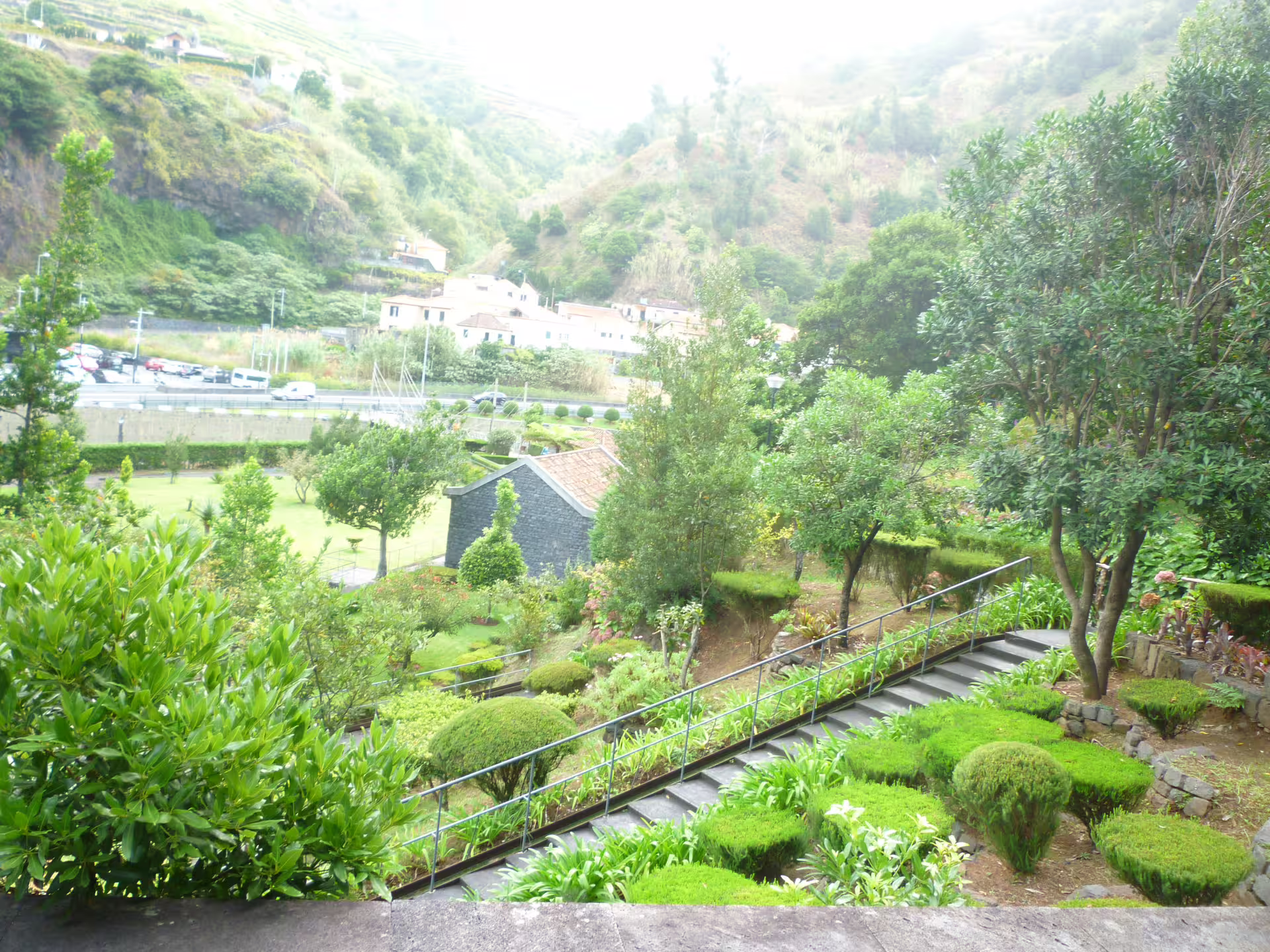 Serene garden with lush foliage and stone paths nestled in a picturesque hillside setting.