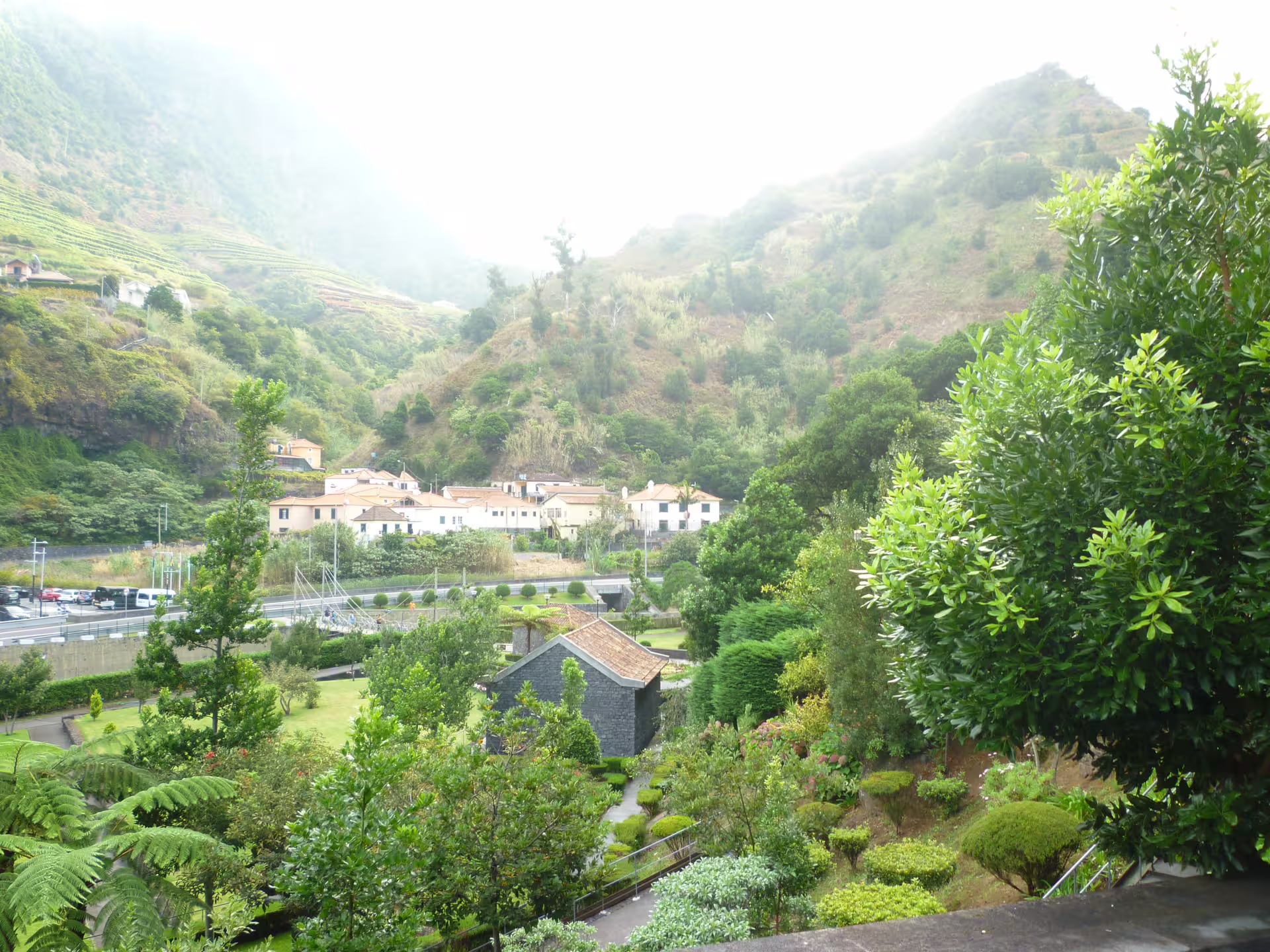 Picturesque hillside village surrounded by verdant gardens and misty mountains on the Around the Island Tour.