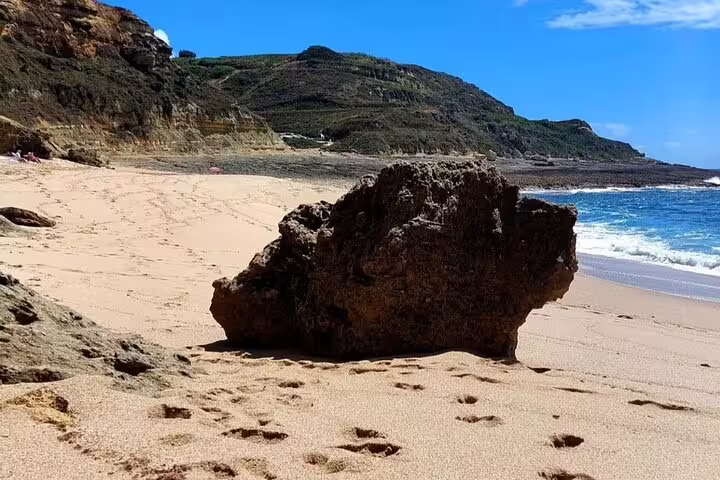 Scenic view of a serene beach with rocky formations in Arrábida, perfect for a private 4X4 Jeep and picnic tour near Lisbon.