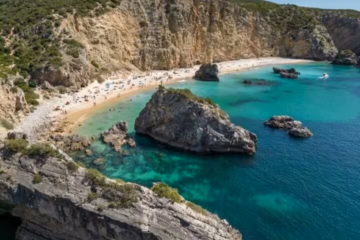 Stunning aerial view of a secluded beach in Arrábida with turquoise waters, seen on the Private Wine Tour from Lisbon.