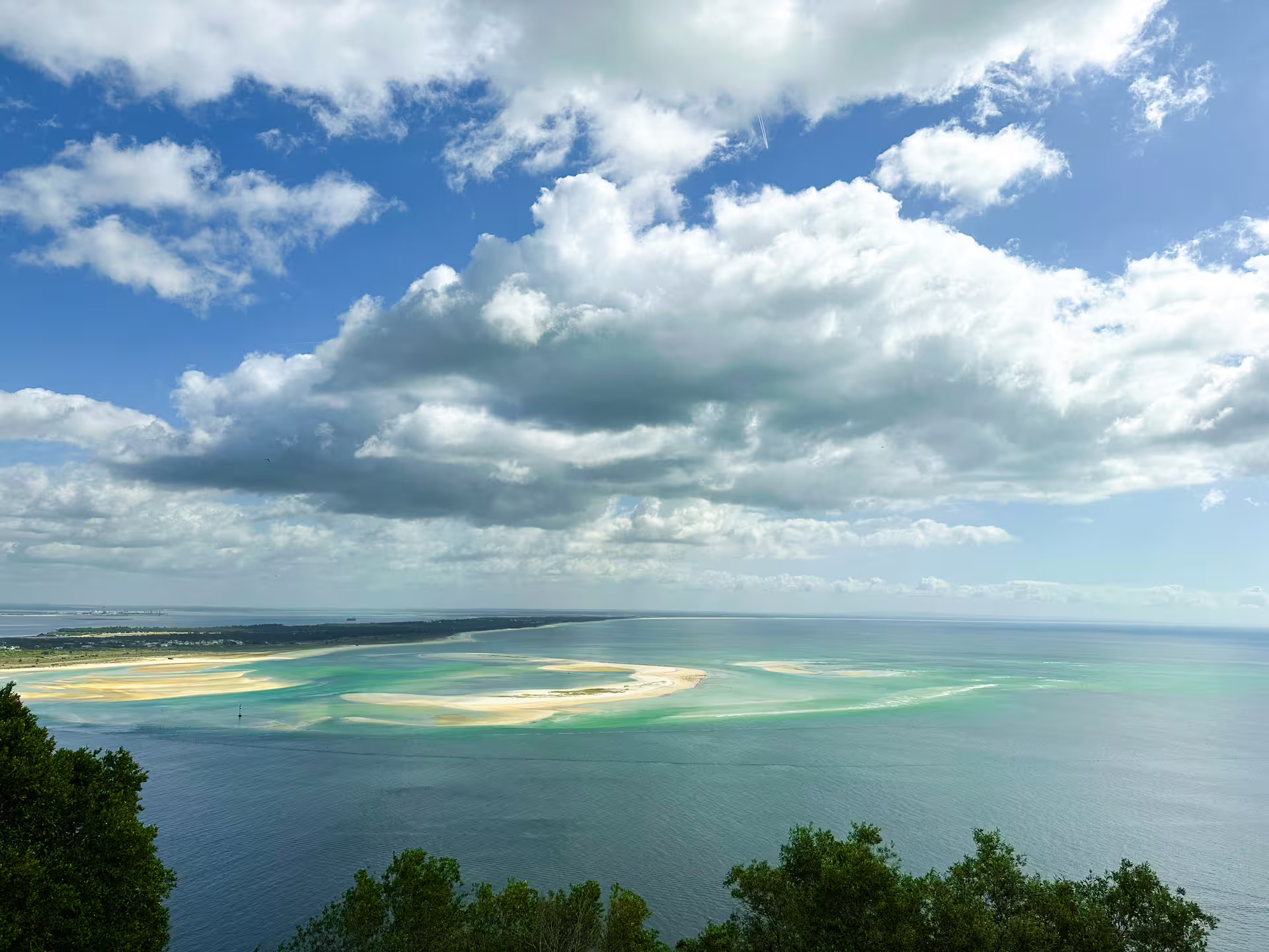 Stunning view of Arrábida's clear blue waters and sandy beaches under a partly cloudy sky on the Blue Coast tour.