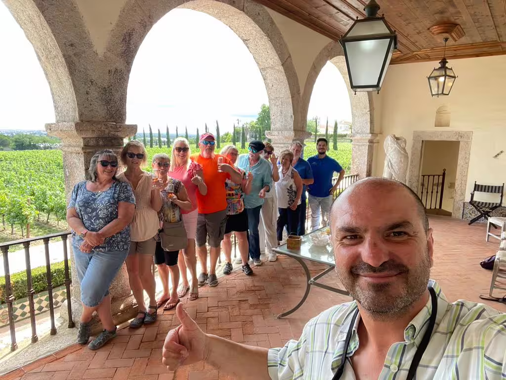 Group of tourists pose at a vineyard terrace with scenic views during the Arrábida and Blue Coast tour.