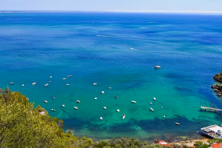 Aerial view of turquoise waters and boats in Arrábida, showcasing the stunning coastal scenery on a Lisbon day tour.