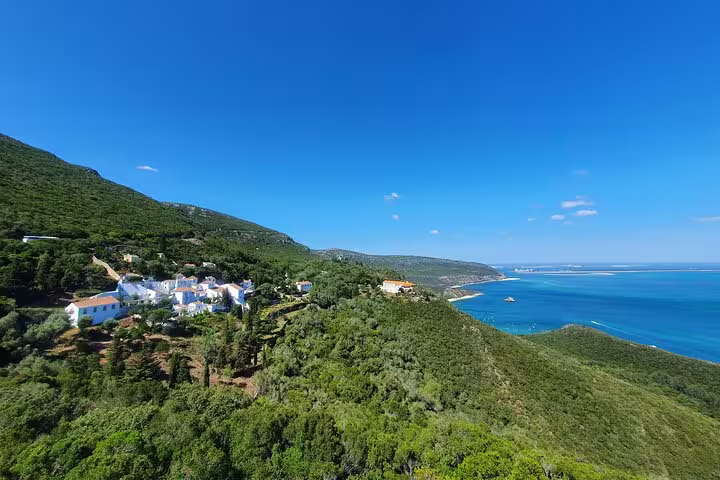 Scenic view of lush green hills and turquoise coastline in Arrábida, Portugal, ideal for small-group day tours from Lisbon.