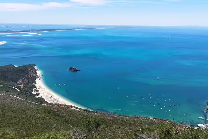 Aerial view of Arrábida's stunning coastline with turquoise waters and sandy beaches, featured in the Setúbal wine tour from Lisbon.