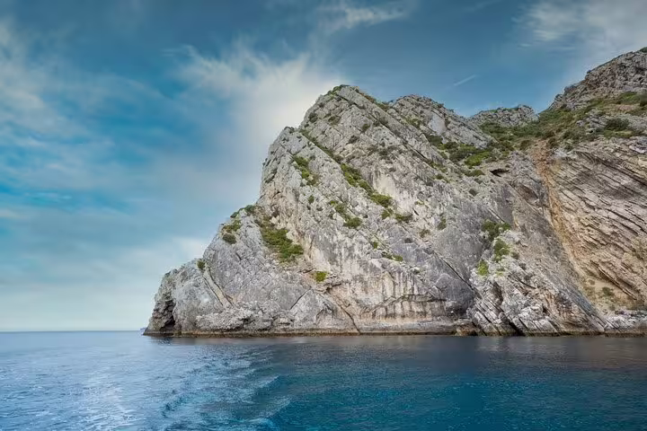 Majestic rocky cliffs meet the serene blue waters in Arrábida Natural Park, perfect for a kayak adventure in Sesimbra.