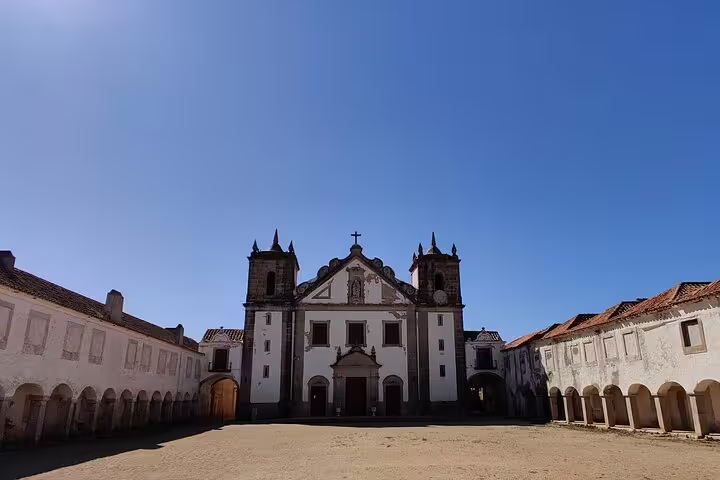 Historic monastery facade under clear blue skies on the Arrabida, Sesimbra, and wine tasting tour from Lisbon.