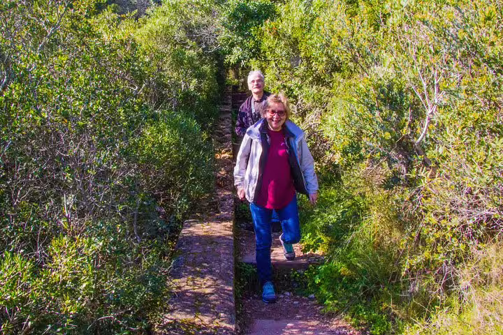 Two people enjoy a scenic hike through lush greenery on the Discover Arrábida tour, exploring the hidden beauty of this secret paradise.
