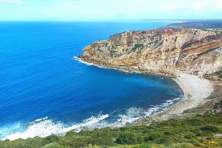 Scenic coastal view of Arrábida's cliffs and turquoise waters on a private 4X4 Jeep and beach picnic tour in Sesimbra-Lisbon.