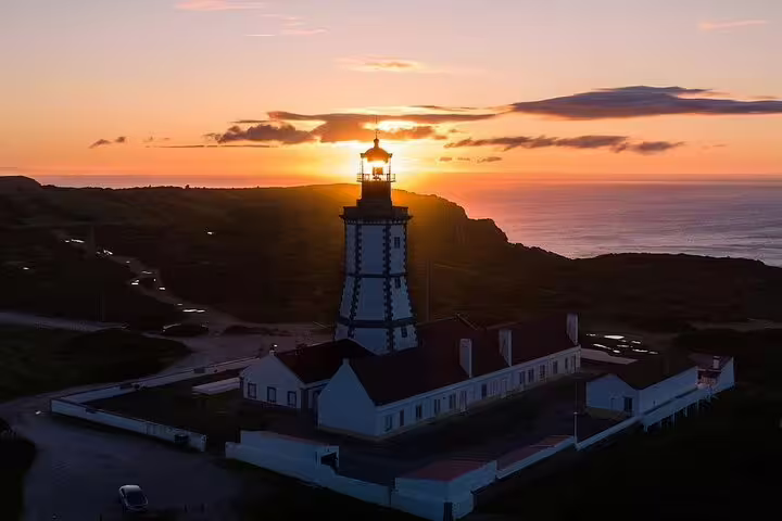 Sunset view of a picturesque lighthouse on the Arrábida & Sesimbra tour, highlighting scenic nature and coastal beauty.