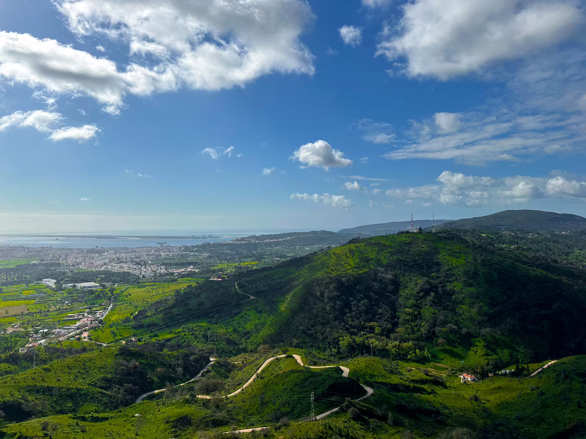 Expansive view of lush hills and the distant coastline from Arrábida, highlighting natural beauty and greenery.