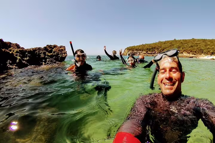 Group of snorkelers enjoying clear waters of Arrábida Natural Park, showcasing adventure and excitement on Lisbon day trip.