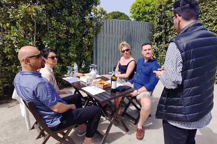 Tourists enjoying a wine tasting experience outdoors on the Setúbal and Arrábida All-Inclusive Food and Wine Tour from Lisbon.