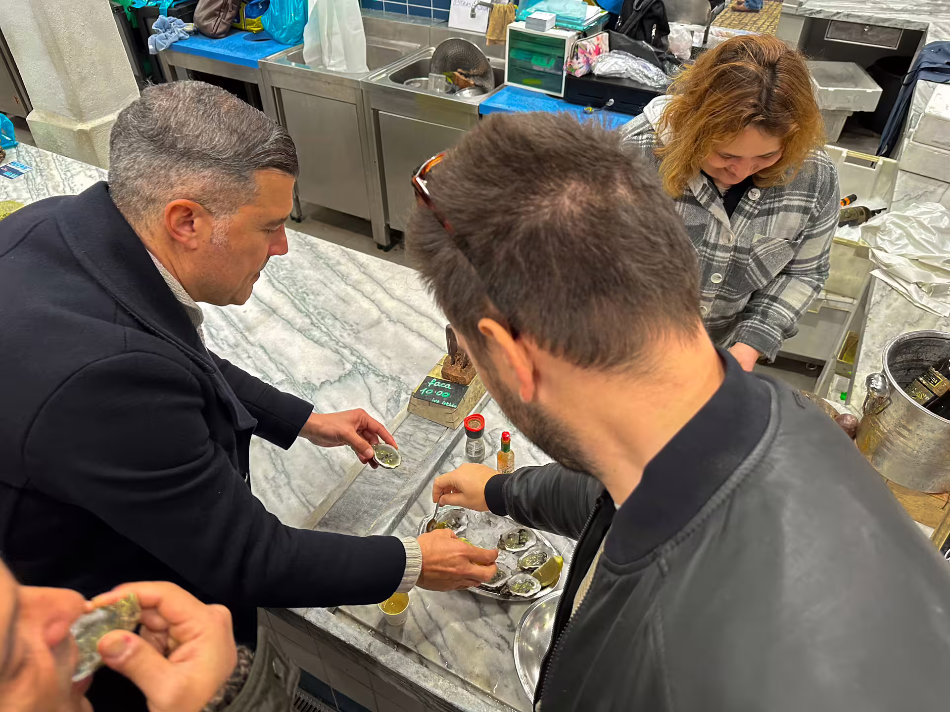 Tourists enjoy fresh oysters at a Setúbal seafood market on the Arrábida and Blue Coast private van tour.