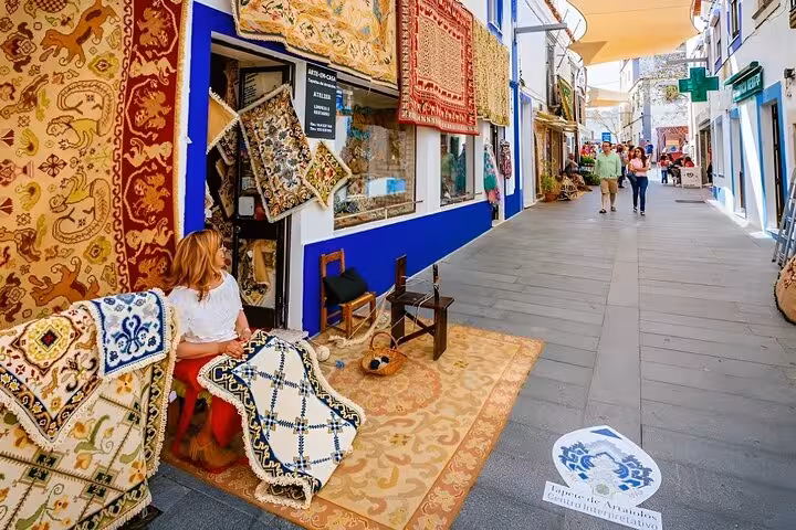 Local artisan weaving colorful rugs in Arraiolos, showcasing traditional craftsmanship on a private walking tour.