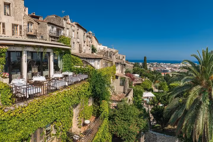 Scenic view of ivy-clad art galleries overlooking lush gardens and Mediterranean coastline.