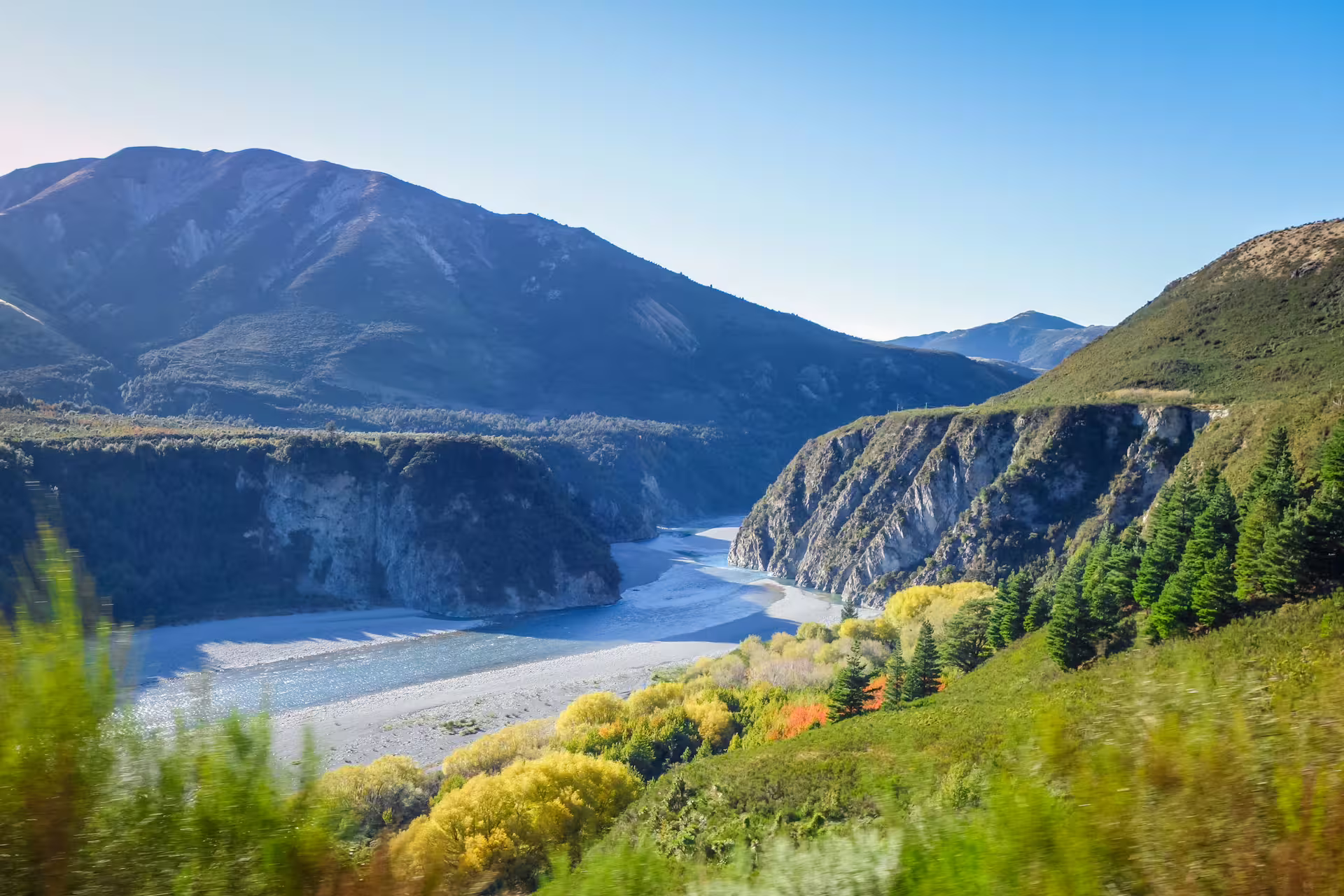 River cutting through vibrant autumn foliage and majestic mountains in Arthur's Pass, ideal for an alpine vista day tour.