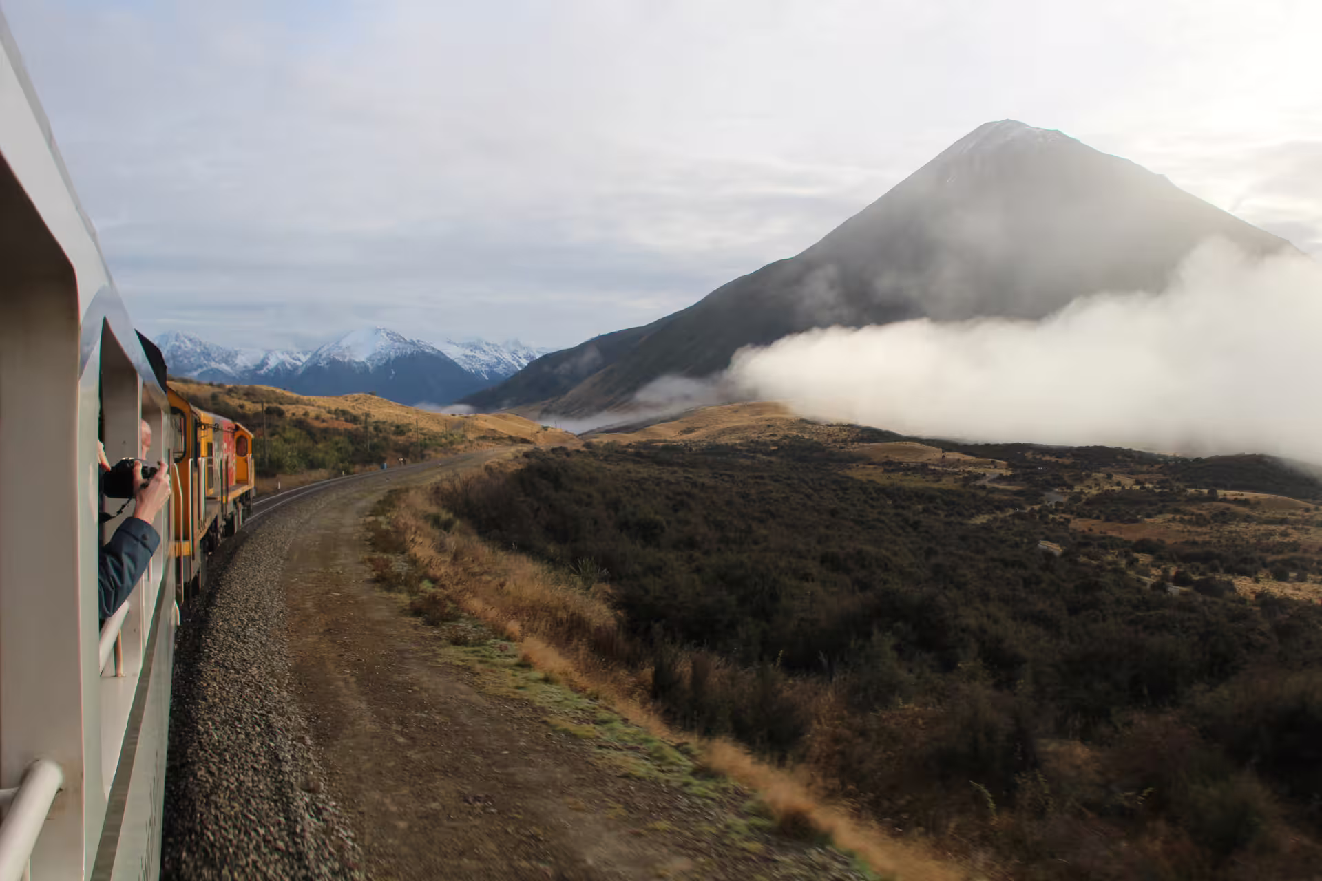 Scenic train journey through Arthur's Pass with stunning alpine views and lush landscapes on a clear day tour.