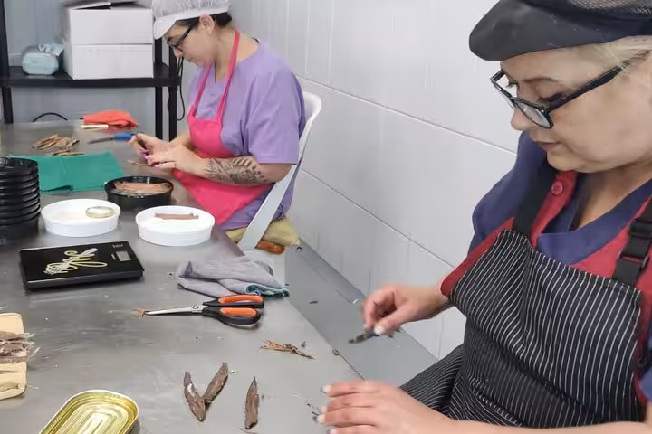 Artisan preparing anchovies by hand during a traditional gastronomy tour in Santander.