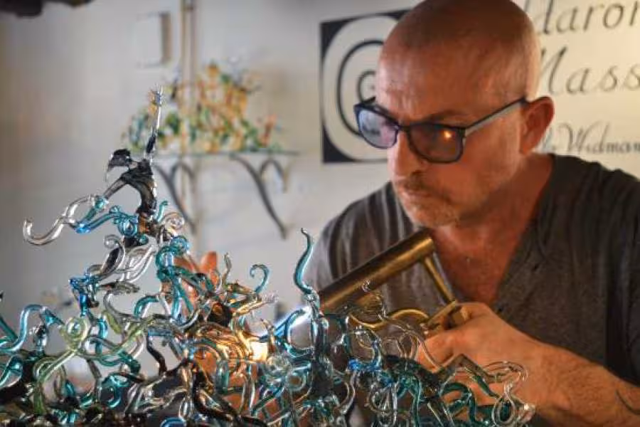 Artisan skillfully shapes intricate glass sculpture with torch, highlighting the artistry of glassmaking in private class.