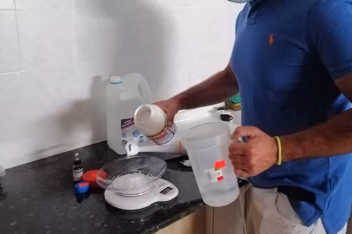 A person in a blue shirt carefully measures ingredients for artisan olive oil soap in a Vieste workshop.