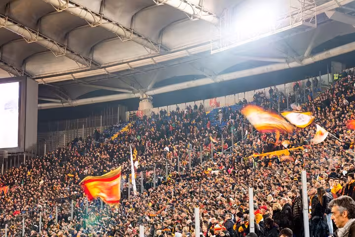 AS Roma fans waving flags in packed Stadio Olimpico stands during Rome football match with local guide