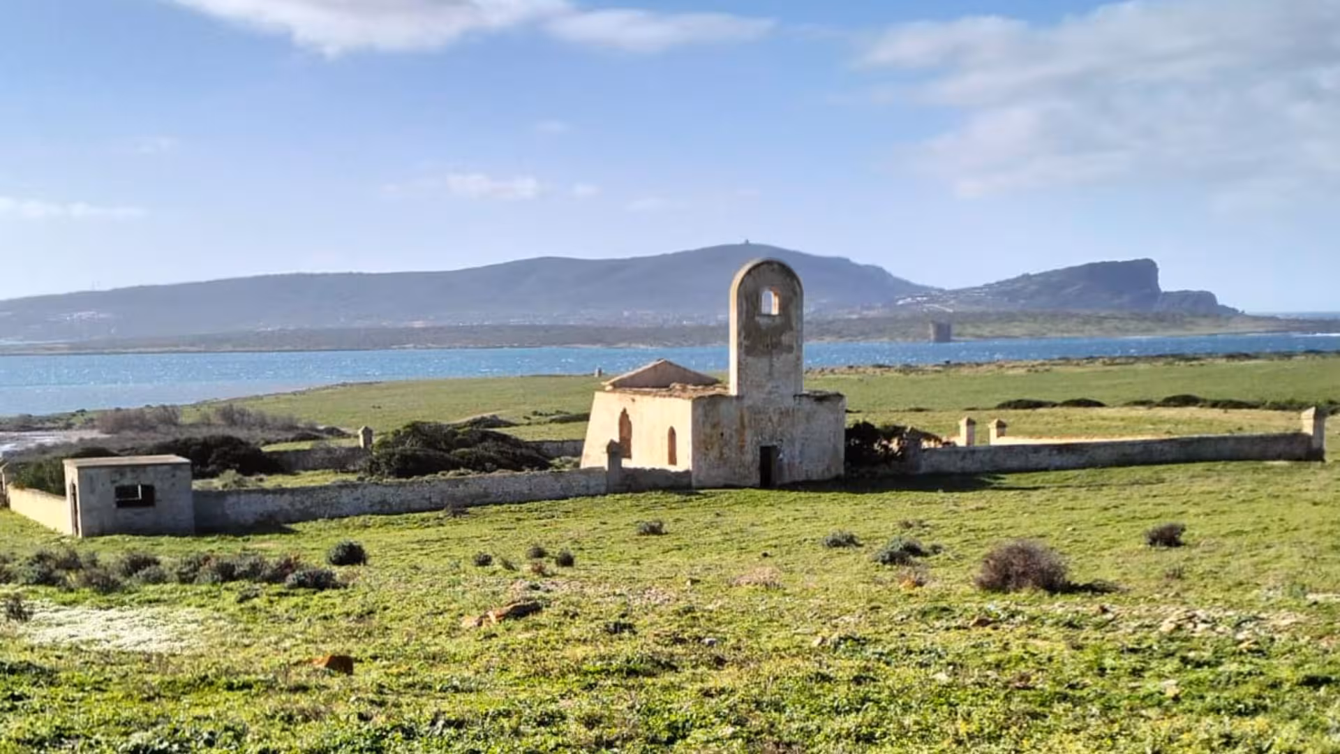 Ancient building ruins on Asinara Island with scenic sea and mountain backdrop, perfect for Porto Torres minivan tour.