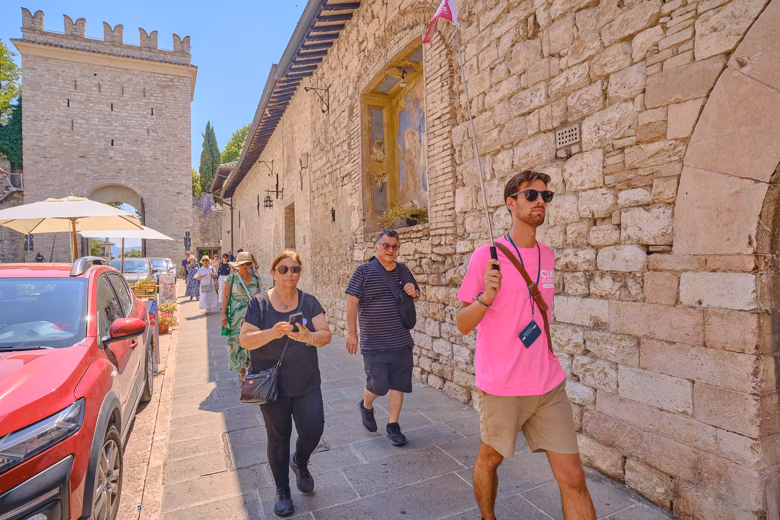 Visitors explore the charming streets of Assisi, guided by a tour leader in the Heart of Umbria region.